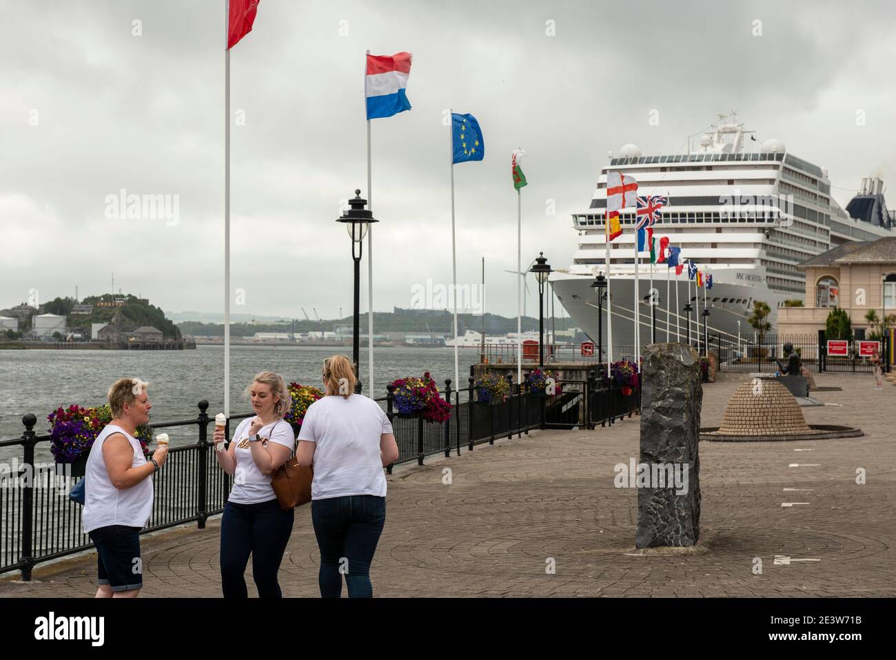 Turisti nella città di Cobh, Irlanda, americani al parco cittadino Promenade con la nave da crociera MSC Orchestra in lontananza Foto Stock