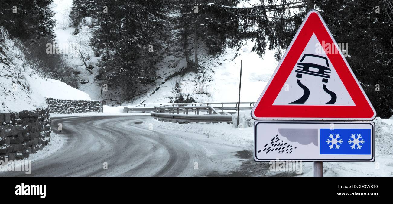 Strada nevosa e curvata con indicazioni stradali Foto Stock