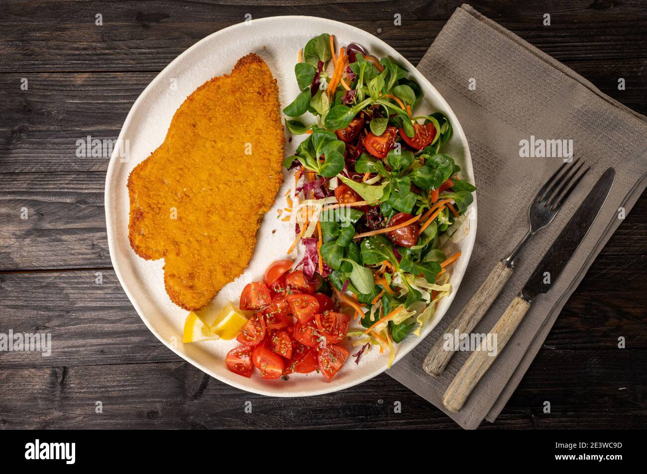 Vista dall'alto di un filetto di pollo milanese con verdure un piatto bianco Foto Stock