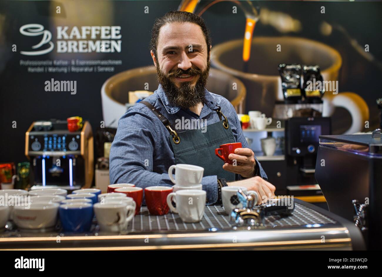 Ritratto di barista sorridente con macchina da caffè, macchina da caffè espresso, macinacaffè, tazze per fare bevande Foto Stock