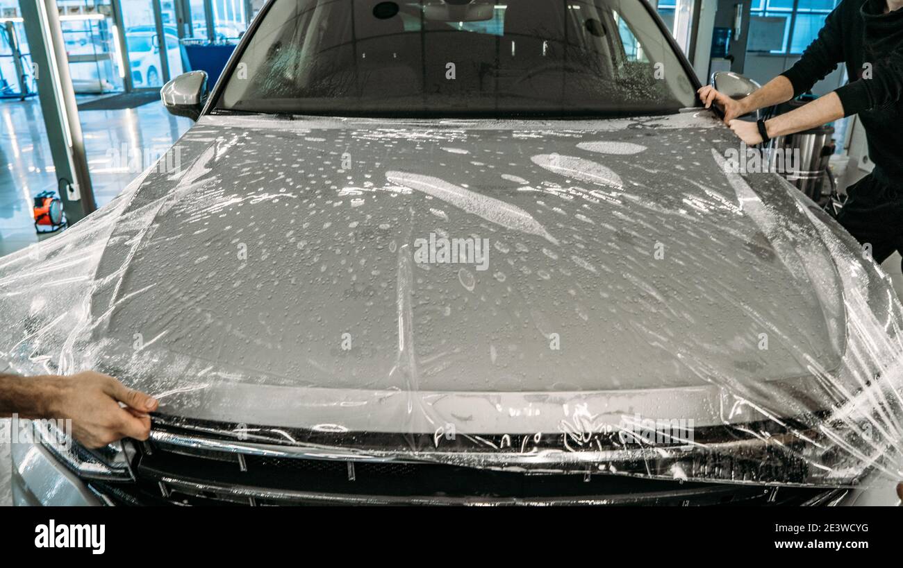 Processo di armamento della cappa con rivestimento in poliuretano trasparente anti-ghiaia in garage di dettaglio auto. Foto Stock