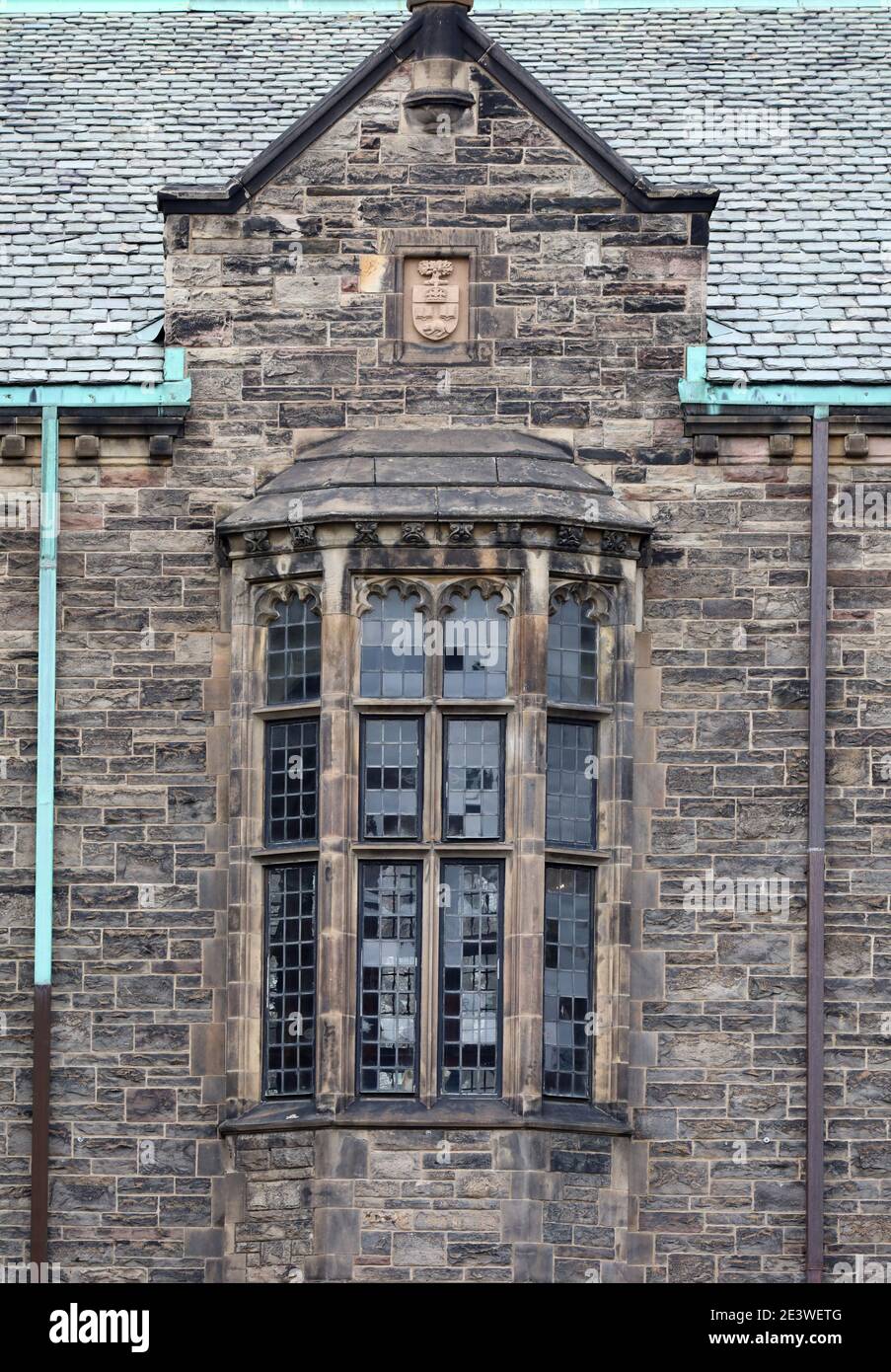 Facciata di un edificio universitario gotico con finestra a bovindo, il Trinity College all'Università di Toronto Foto Stock