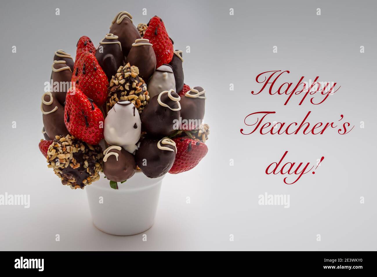 Happy Teacher's Day bigliettino con scritta rossa; UN mazzo di fiori commestibili, arrangiamento di fragole ricoperte di cioccolato isolato su sfondo bianco Foto Stock