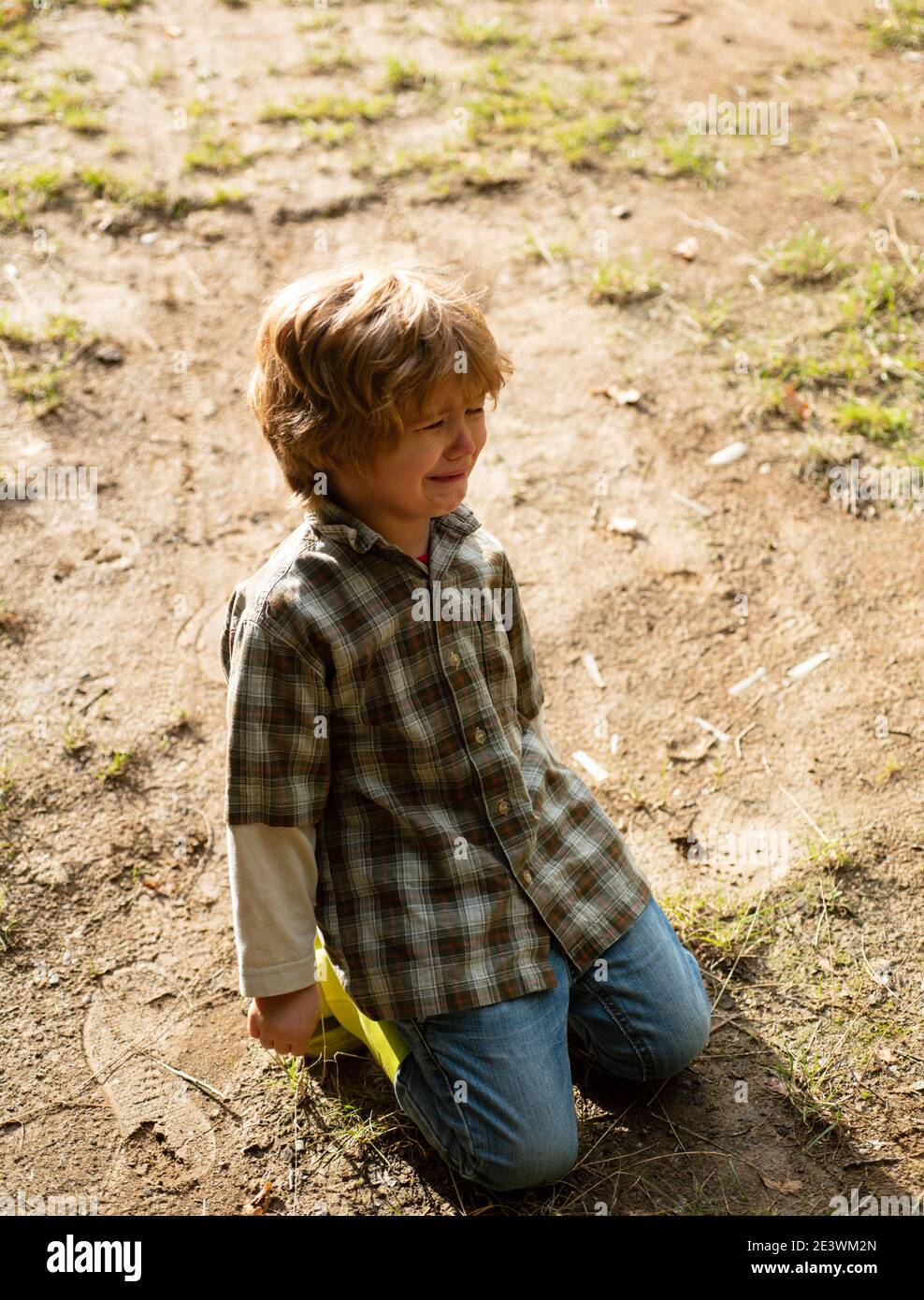 Un bambino sta cadendo sulla strada. Concetto emotivo per i bambini. Il ragazzino biondo piange con le lacrime. Bambino sconvolto. Violenza in famiglia sui bambini. Conc Foto Stock