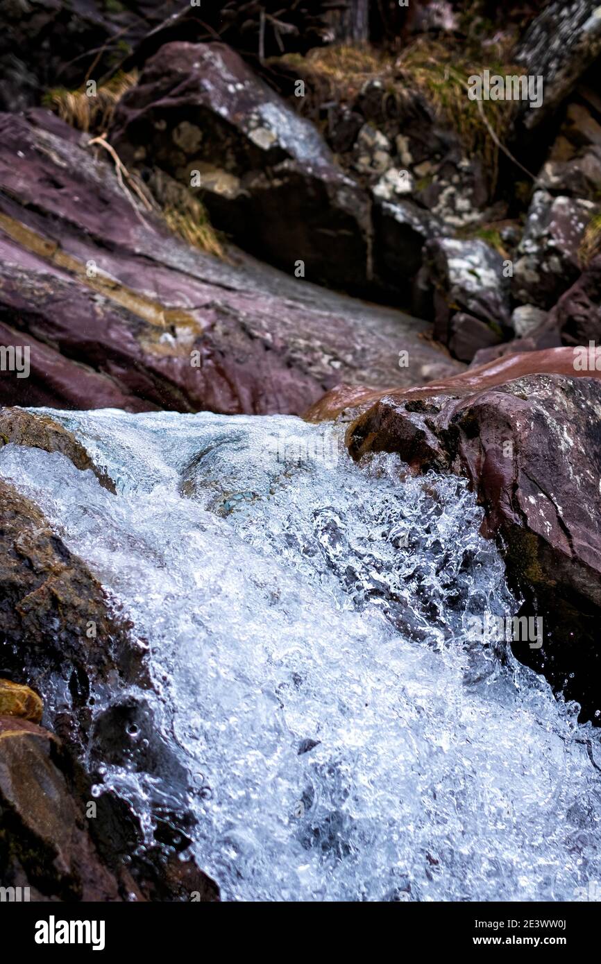 particolare di un torrente montano di acqua cristallina che scorre tra le rocce, verticale Foto Stock