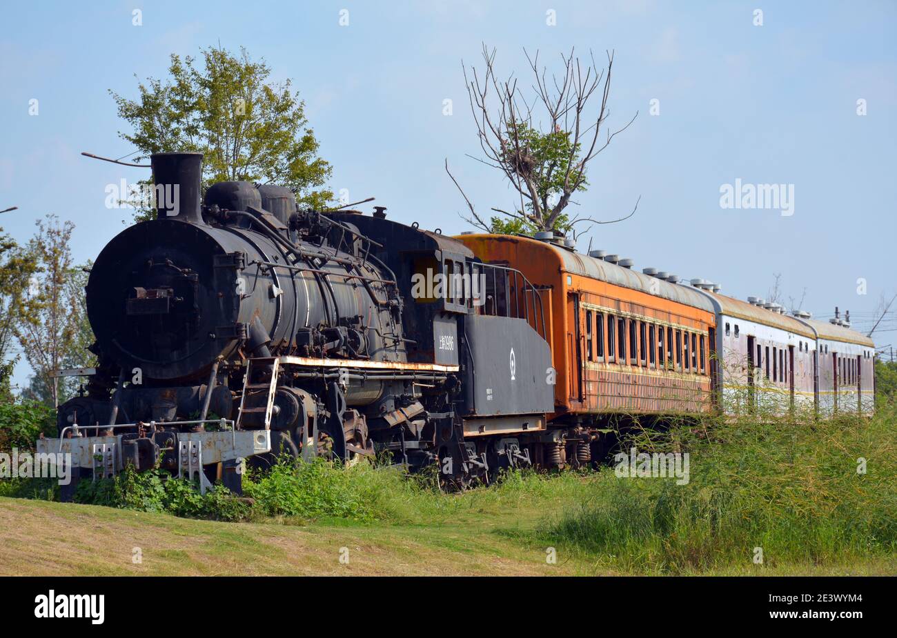 Vecchio treno a vapore e carrozze sul lato della strada a Jiaxing, Cina. Abbandonato e lasciato agli elementi. Corroso, arrugginito e ben intemperie. Foto Stock