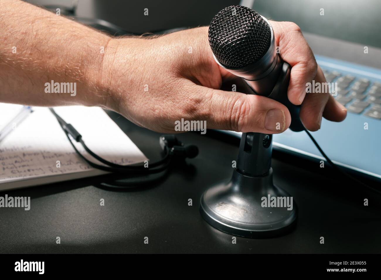 Una mano dell'uomo che ospita un piccolo microfono da tavolo prima di una conferenza virtuale. Stile moderno, concetto di comunicazione e conferenza. Foto Stock
