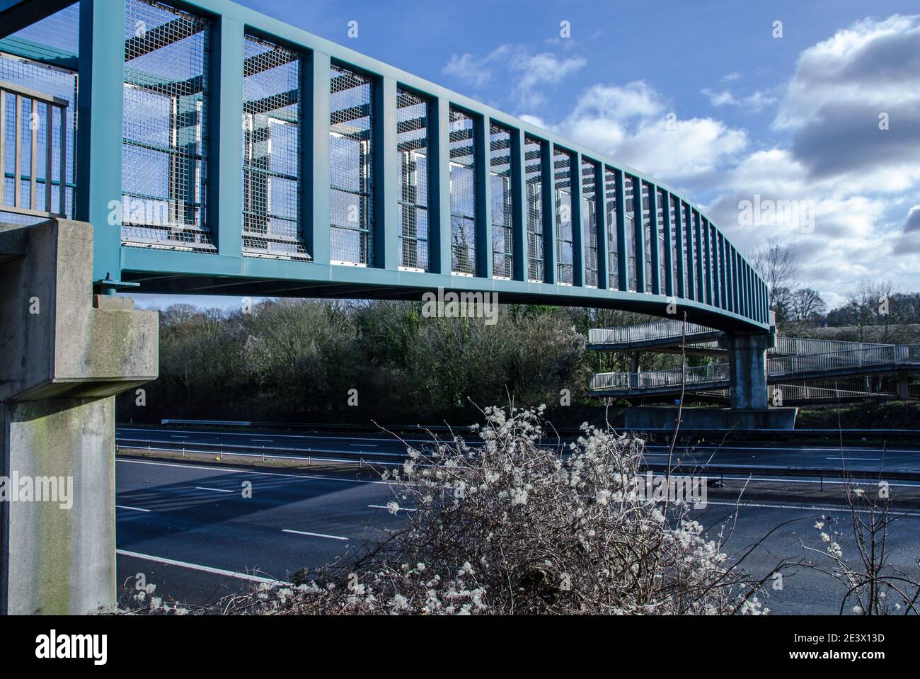 Un ponte pedonale che attraversa l'autostrada M3 a Basingstoke, Hampshire, in una giornata soleggiata e invernale. Foto Stock