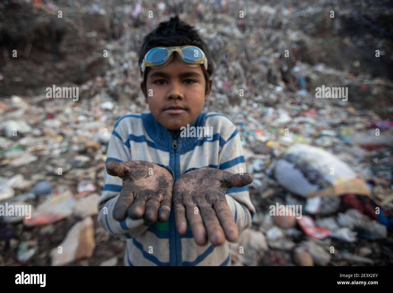 Neu Delhi, India. 18 gennaio 2021. Il decennale Shekh Zahid mostra le sue mani sporche dal raccogliere immondizia al sito di Bhalswa. Il quarto classificato di Malda nel Bengala Occidentale, il cui padre lavora come pilota di risciò, ha iniziato a lavorare durante la chiusura delle scuole nell'ottobre 2020. La sua famiglia lo mandò a Delhi per stare con uno zio che già lavorava come picchiatore di straccio. Shek guadagna 150 rupie al giorno raccogliendo materiale riciclabile dalla discarica dei rifiuti. Credit: Vijay Pandey/dpa/Alamy Live News Foto Stock