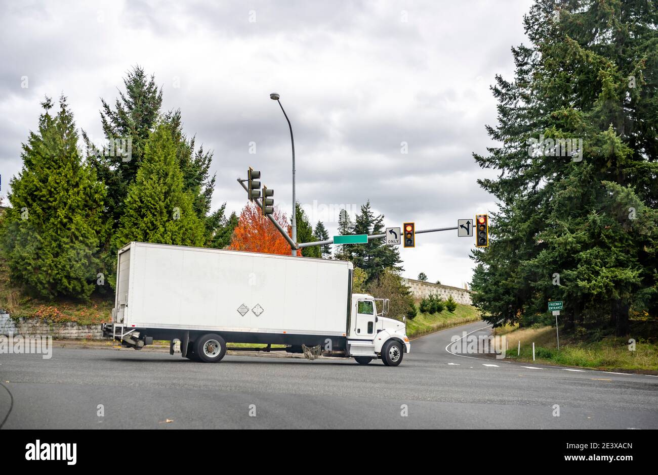 Carrello semirimorchio commerciale Big RIG White Day Cab per uso locale consegne con carrello lungo all'entrata dell'autostrada da strada cittadina con traffico Foto Stock