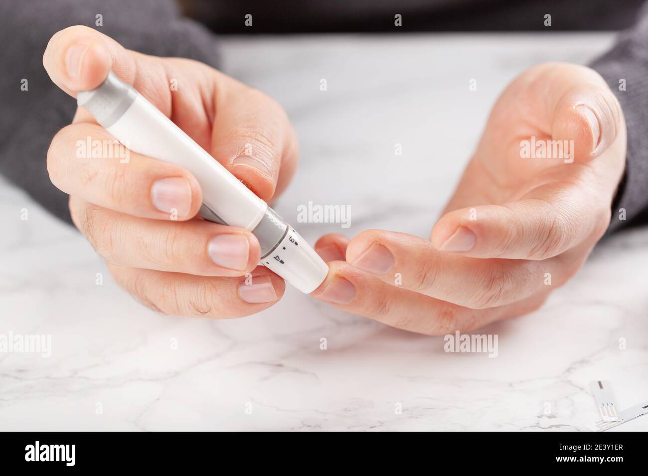 le mani dell'uomo usando il lancet sul dito per controllare il livello di zucchero di anima o i chetoni dal glucometro. medicina diabete keto dieta assistenza sanitaria a casa Foto Stock