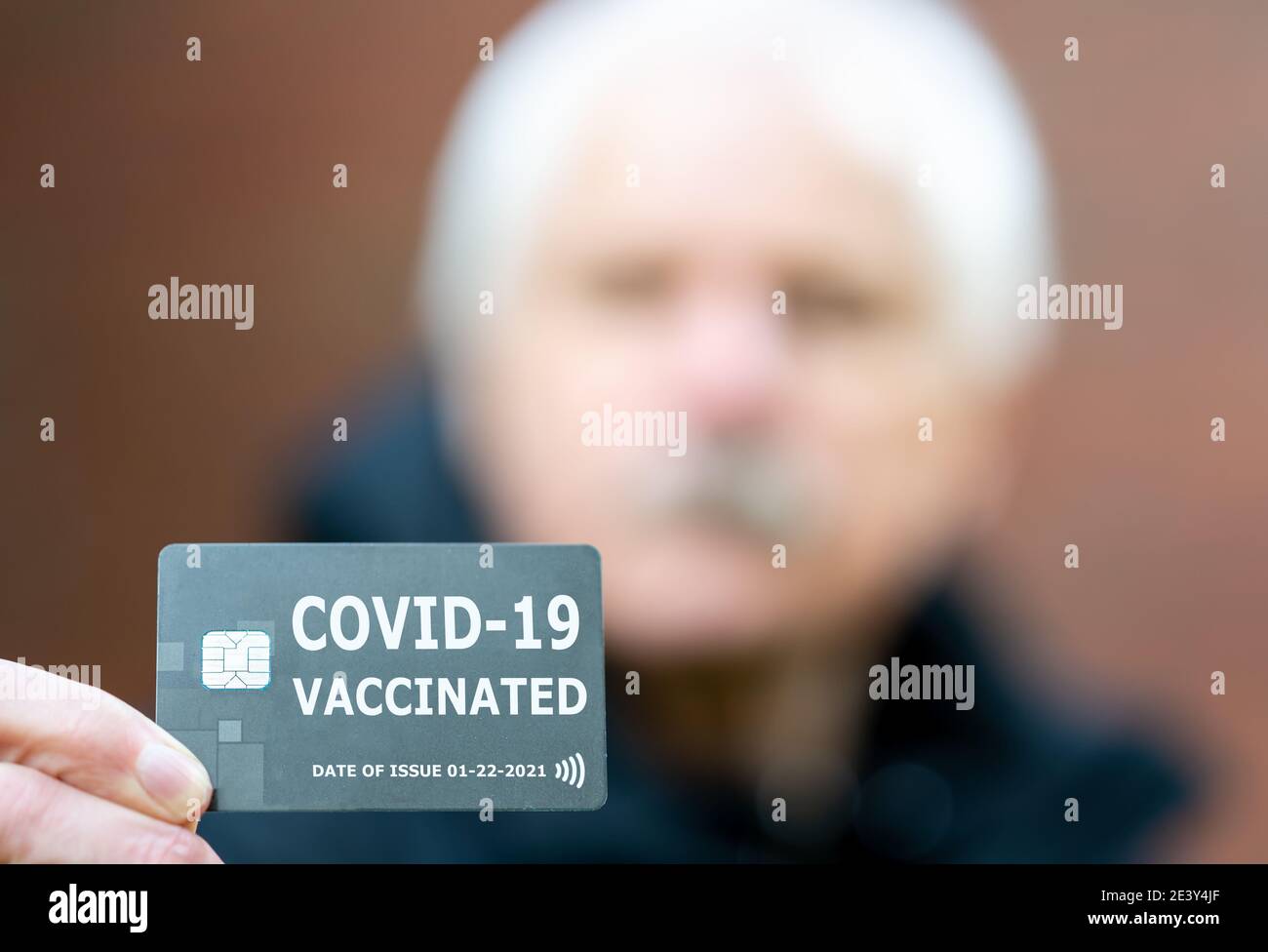 Uomo anziano che mostra un certificato di vaccinazione, che indica una vaccinazione contro il covid-19. Foto Stock