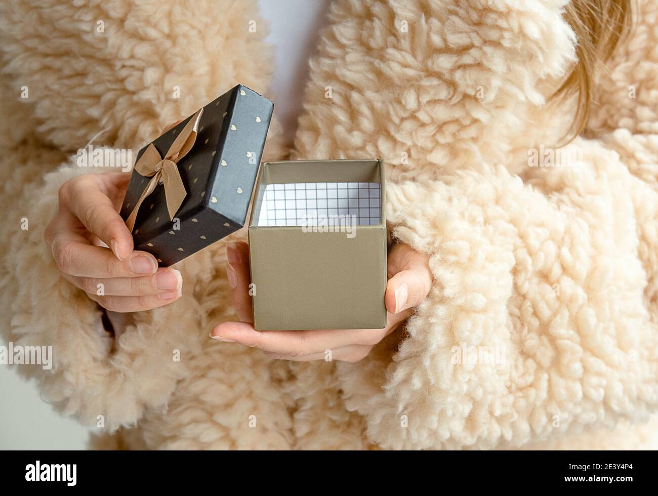 Ragazza in pelliccia sintetica che apre una piccola scatola regalo con  nastro a scatola Foto stock - Alamy