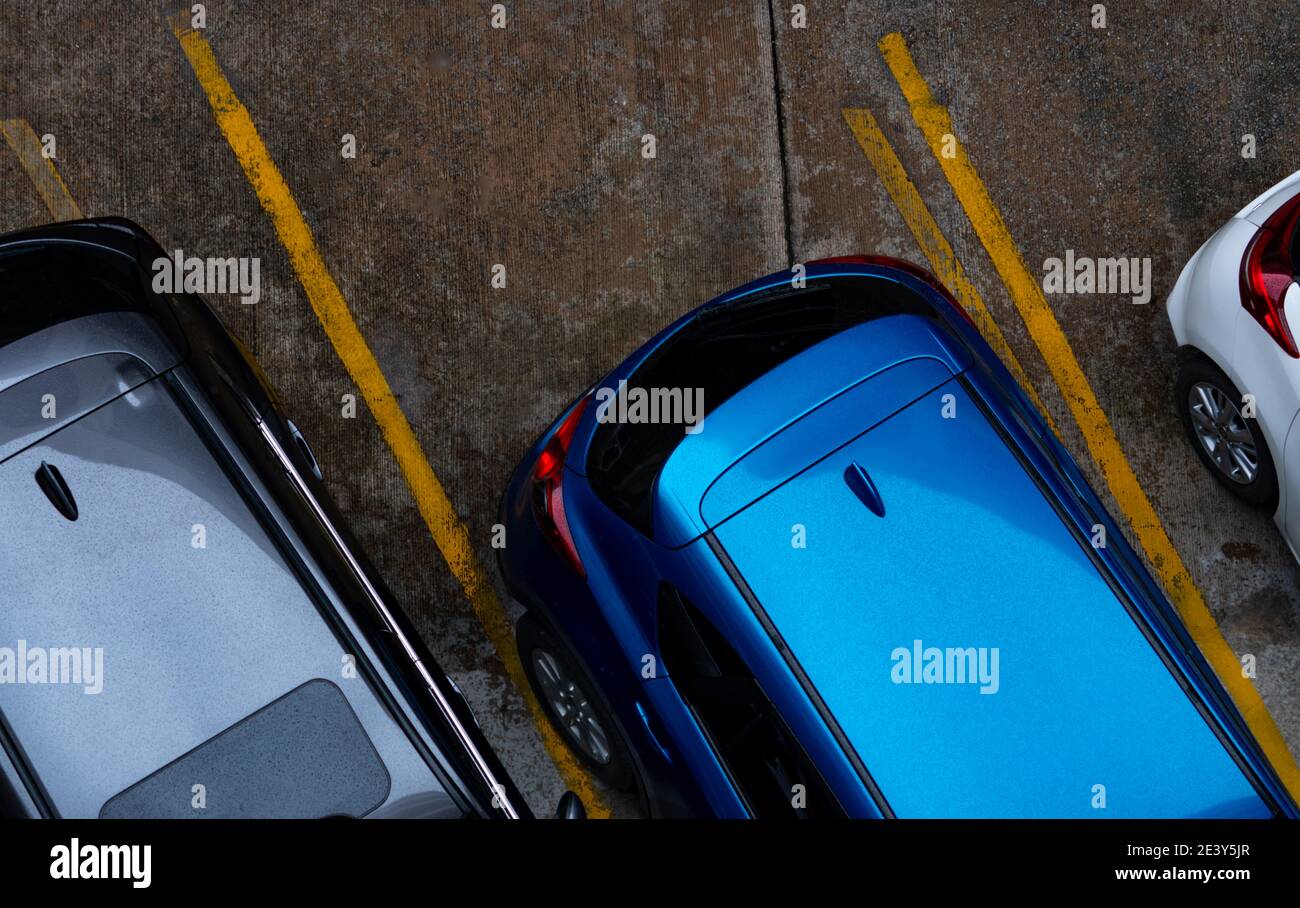 Vista dall'alto dell'auto parcheggiata nel parcheggio in cemento con una linea gialla di segnaletica stradale sulla strada. Vista dall'alto dell'auto in fila nel parcheggio. Foto Stock