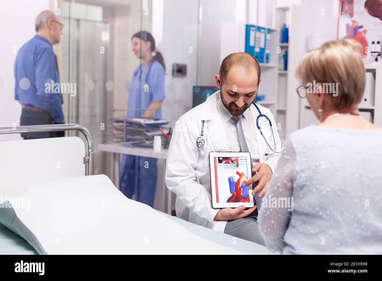 Medico che spiega il trattamento per la malattia di cuore alla donna anziana in sala di consultazione. Cardiologo che indossa stetoscopio discutere con il paziente di malattie cardiache non sane. Foto Stock