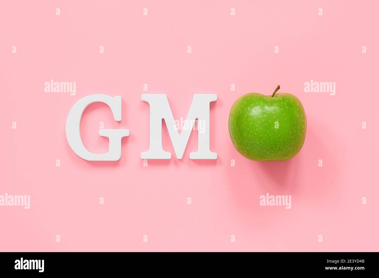GMO tex da lettere di volume bianche e mela verde su sfondo rosa. Concetto di alimenti o frutti geneticamente modificati. Vista dall'alto spazio di copia Flat Lay. Foto Stock