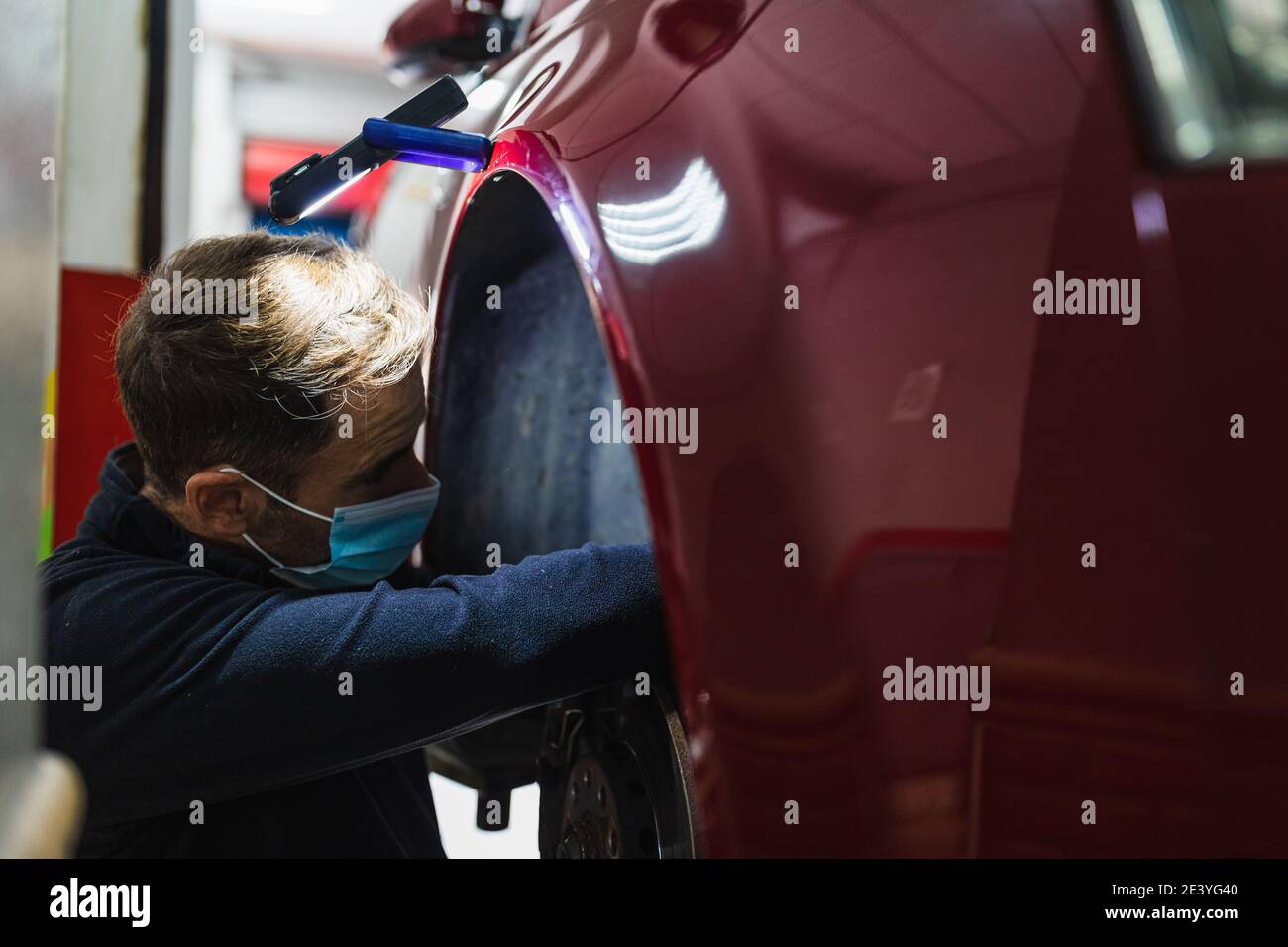 meccanico che ripara la sospensione dell'auto. Concentratevi sulle mani. COVID 19 Foto Stock