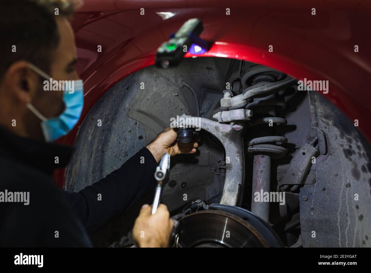 meccanico che ripara la sospensione dell'auto. Concentratevi sulle mani. COVID 19 Foto Stock