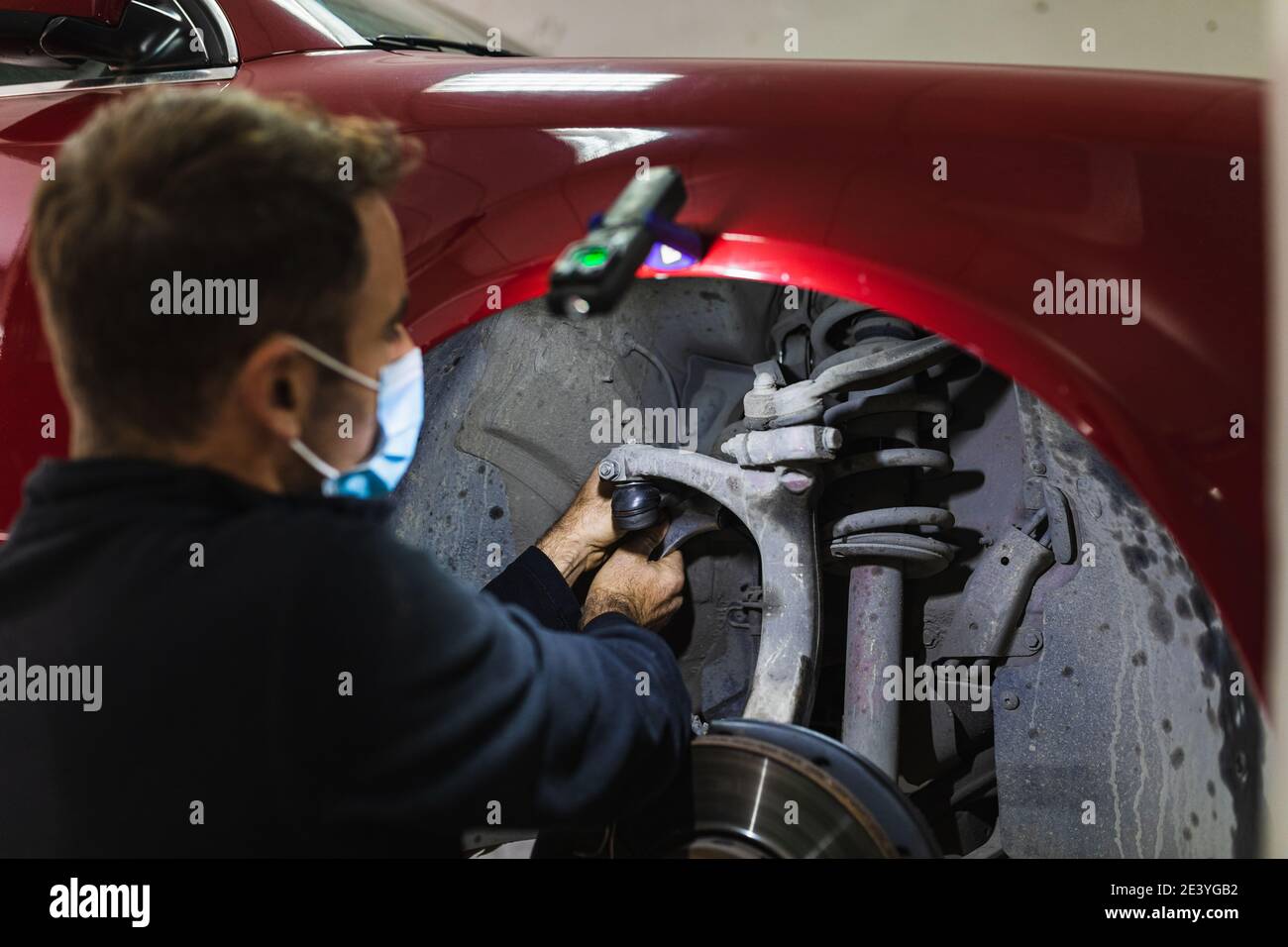 meccanico che ripara la sospensione dell'auto. Concentratevi sulle mani. COVID 19 Foto Stock