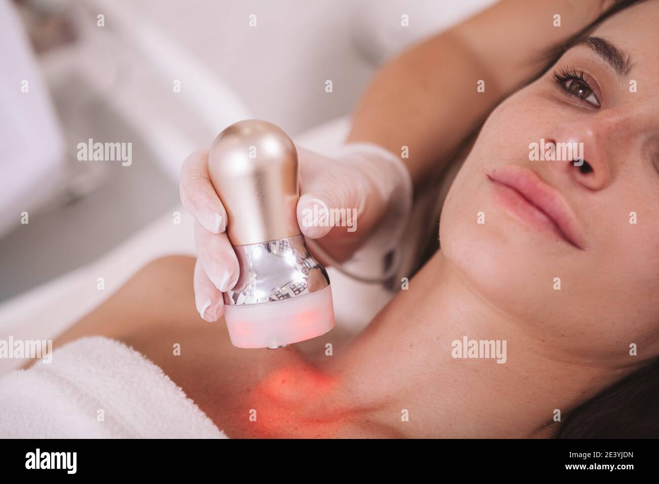 Primo piano corto di una donna che ottiene trattamento di serraggio della pelle da parte del cosmetologist. Estetista che fa la procedura di sollevamento rf su paziente femminile Foto Stock