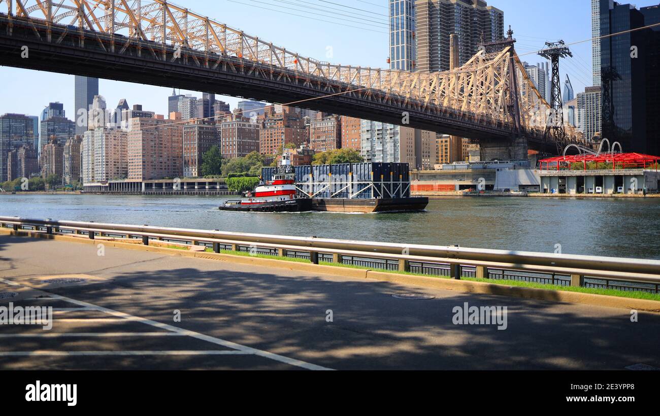 New York, NY, Stati Uniti d'America - 20 gennaio 2021: Rimorchiatore che spinge una chiatta sul fiume est sotto il ponte di Queensboro visto da Roosevelt Island Foto Stock