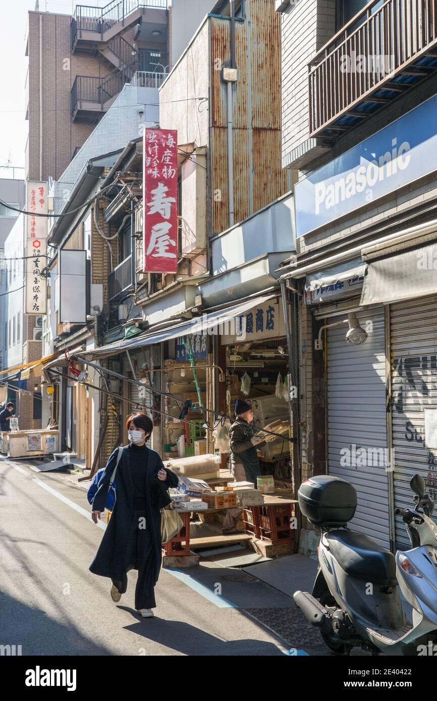 Tokyo, Giappone. 21 Gennaio 2021. Donna che indossa una maschera come misura contro Covid19 cammina davanti a un negozio chiuso nel mercato esterno di Tsukiji a Tokyo.Tsukiji è priva di molta attività, in quanto la maggior parte delle aziende sono state spostate al mercato di Toyosu a causa dei giochi olimpici. Il mercato è comunque ancora aperto con molti negozi chiusi alla ricerca di nuovi inquilini. Credit: SOPA Images Limited/Alamy Live News Foto Stock