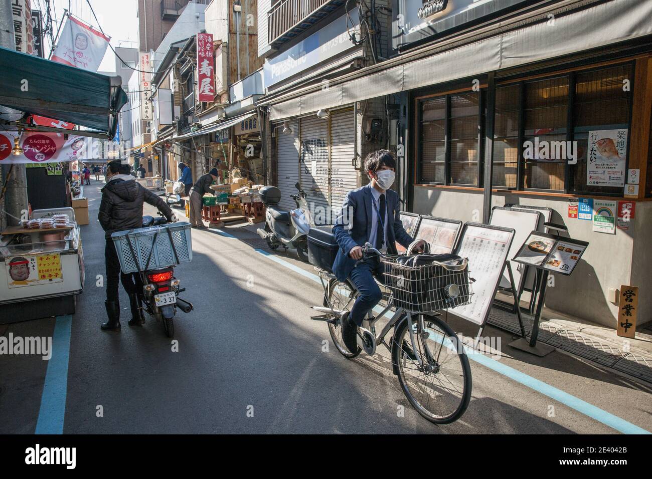 Tokyo, Giappone. 21 Gennaio 2021. Un uomo che indossa una maschera come misura contro Covid19 corre attraverso un mercato esterno di Tsukiji non così occupato a Tokyo.Tsukiji è privo di molta attività come la maggior parte delle imprese sono state spostate al mercato di Toyosu a causa dei giochi olimpici. Il mercato è comunque ancora aperto con molti negozi chiusi alla ricerca di nuovi inquilini. Credit: SOPA Images Limited/Alamy Live News Foto Stock