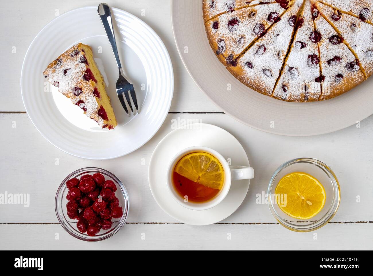 Vista dall'alto della torta di ciliegie a fette, fetta di torta su un piatto e tè al limone. Messa a fuoco selettiva, orientamento orizzontale. Foto Stock