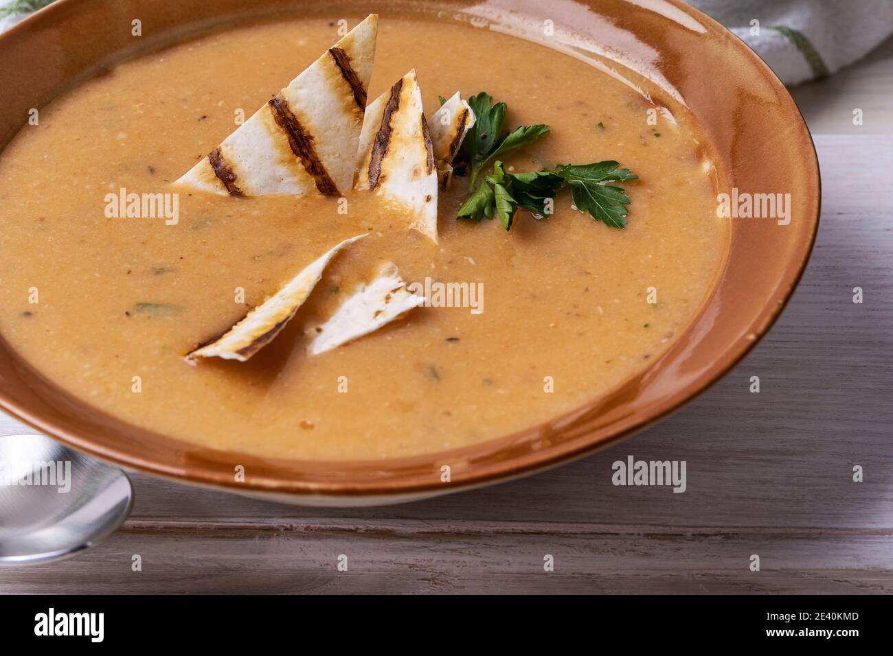 Ciotola di zuppa di fagioli servita con pane pita su sfondo di legno bianco, pasto vegano sano, cibo a base di piante Foto Stock