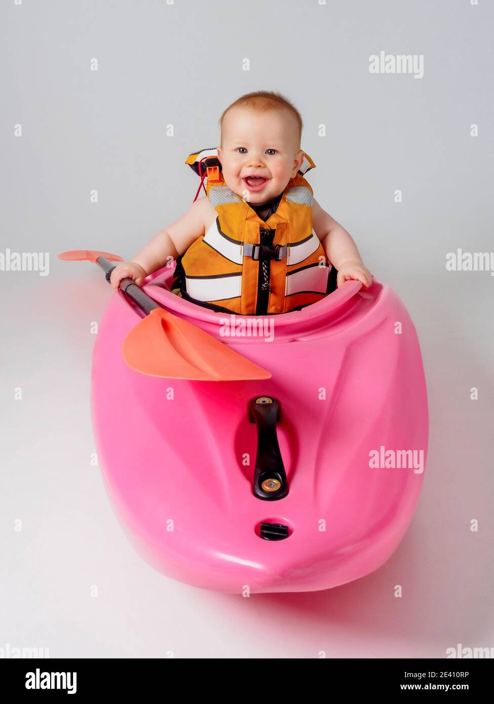 Bambino in kayak rosa con pagaia arancione Foto Stock