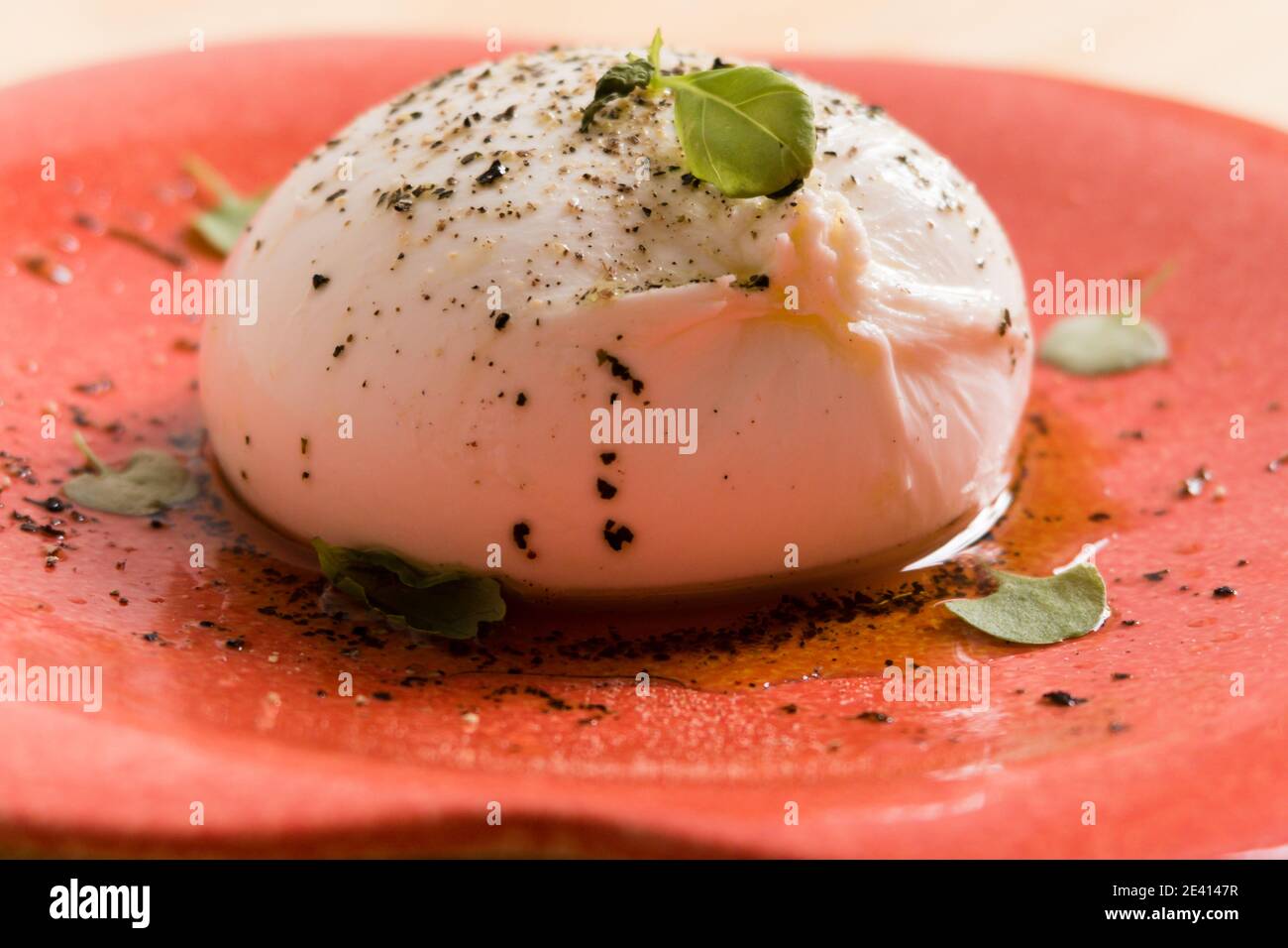 Una mozzarella di bufala su un piatto con basilico Foto Stock