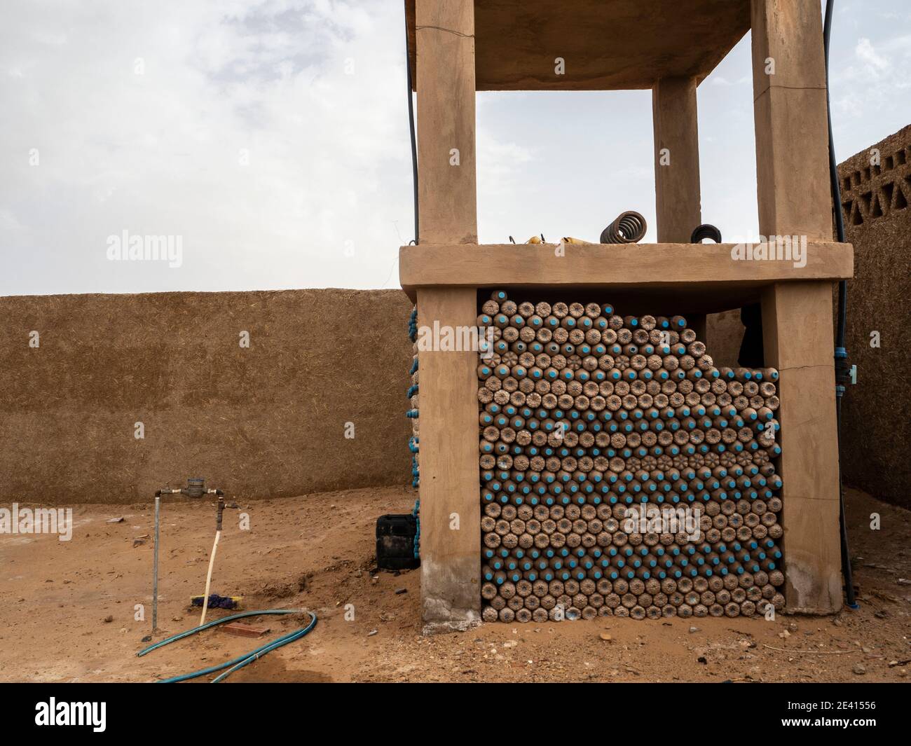 Riutilizzo di contenitori di plastica per l'acqua per la costruzione di pareti in Deserto del Sahara Foto Stock