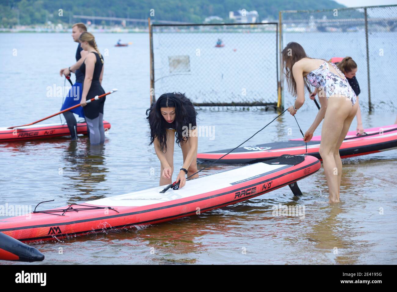 Giovani ragazze che mettono il bordo del SUP sull'acqua che si preparano per l'addestramento. 5 giugno 2020. Kiev, Ucraina Foto Stock