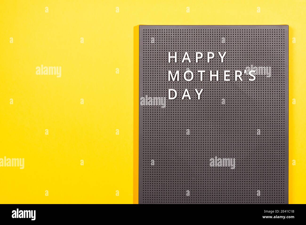 Cartellone in plastica grigio con citazioni bianche Happy Mother's Day su sfondo giallo illuminante. Foto Stock
