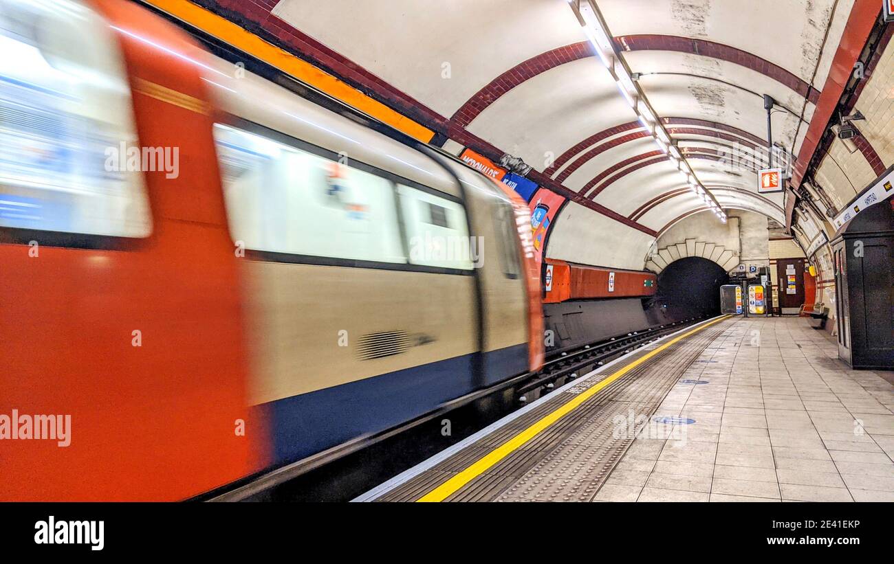 Un treno della metropolitana che arriva a una stazione della metropolitana di Londra con motion blur. La piattaforma luminosa e ben illuminata è vuota di passeggeri. Northern Line, Hampstead. Foto Stock