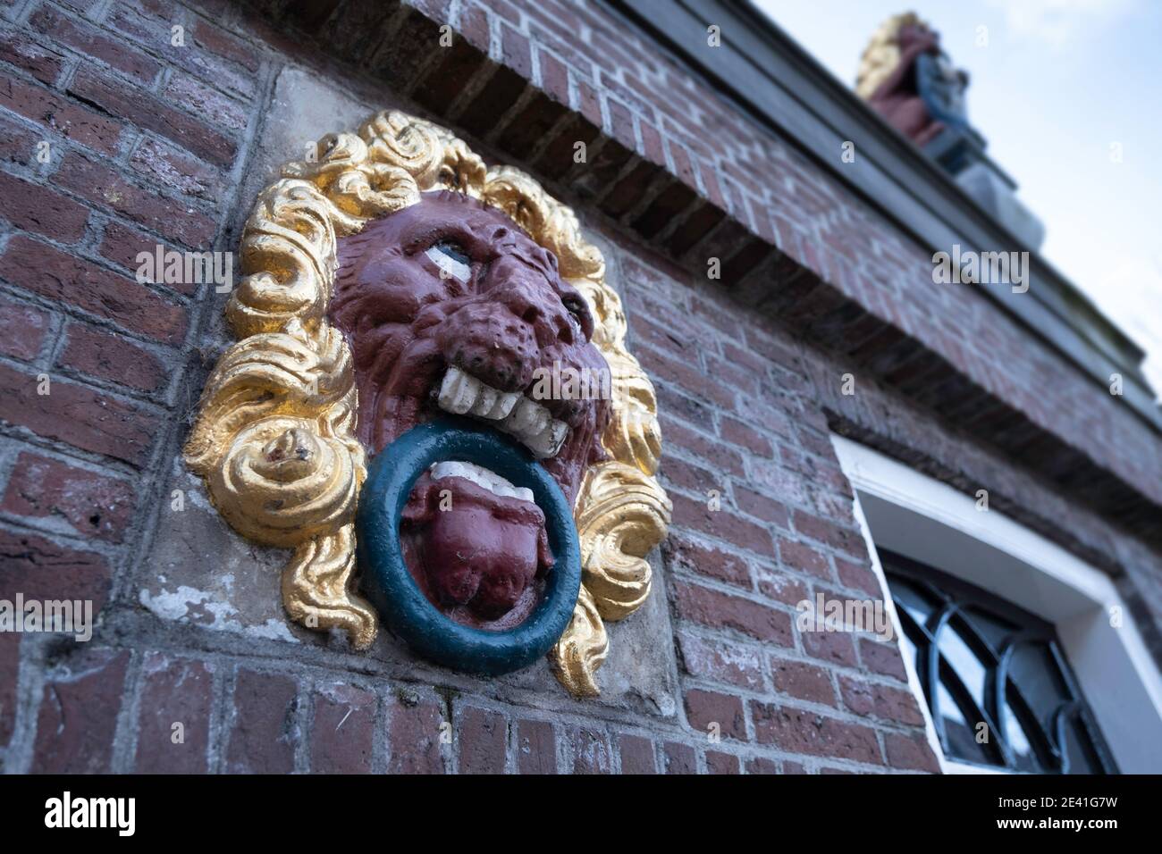 Scultura della testa di un leone nella facciata dell'ex municipio monumentale o casa di corte del comune di Balk. Mettere a fuoco i denti bianchi Foto Stock