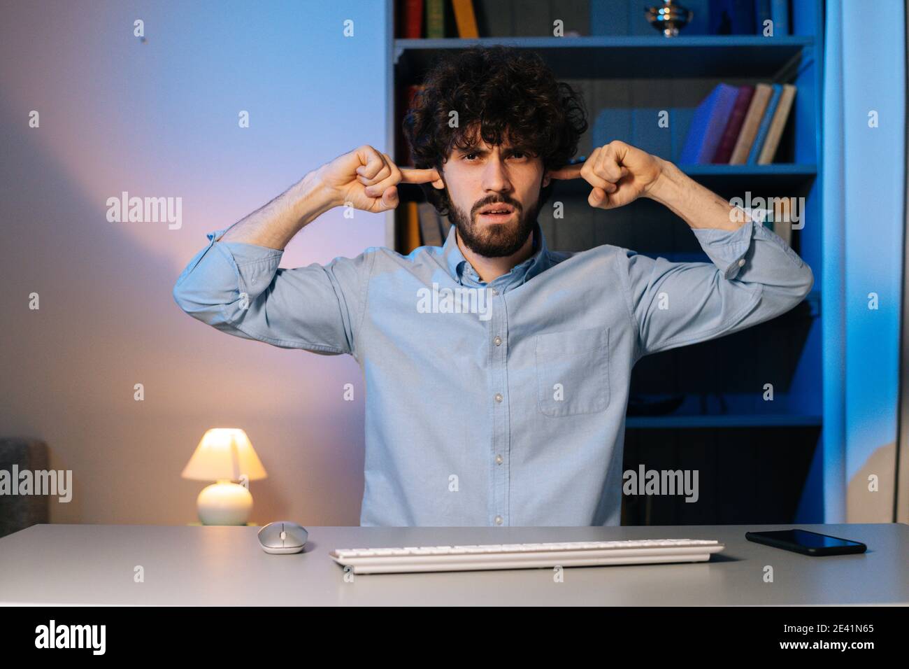 Vista frontale di un giovane stanco che lavora al computer, che si sente sonnolento in ufficio a casa di notte Foto Stock