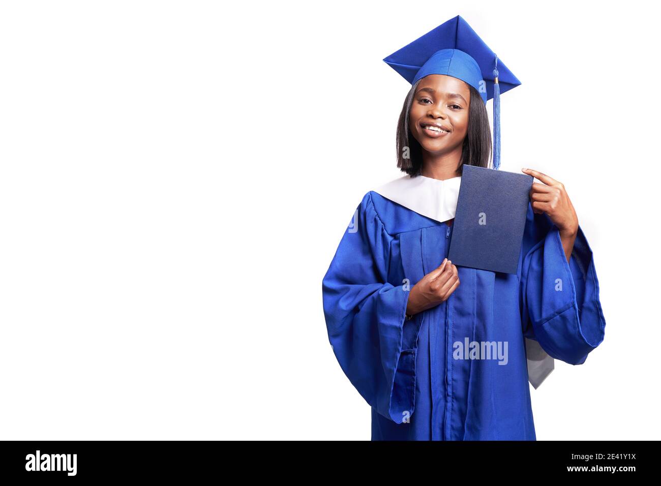 Afroamericana bella donna in una veste blu e cappello, su uno sfondo bianco isolato sorride e mostra diploma Foto Stock