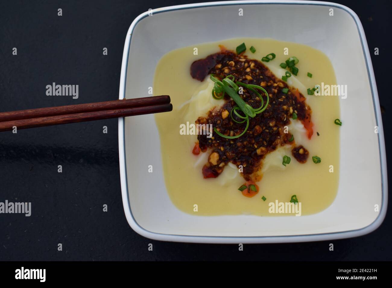 Cibo vegano: Tofu liquido con peperoncino servito sul piatto con bastoncini Foto Stock