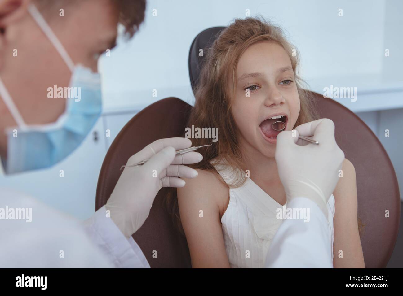 Dentista che esamina i denti di una giovane bella ragazza. Adorabile bambina che ottiene controllo dentale da dentista professionista. Concetto di assistenza sanitaria per bambini Foto Stock