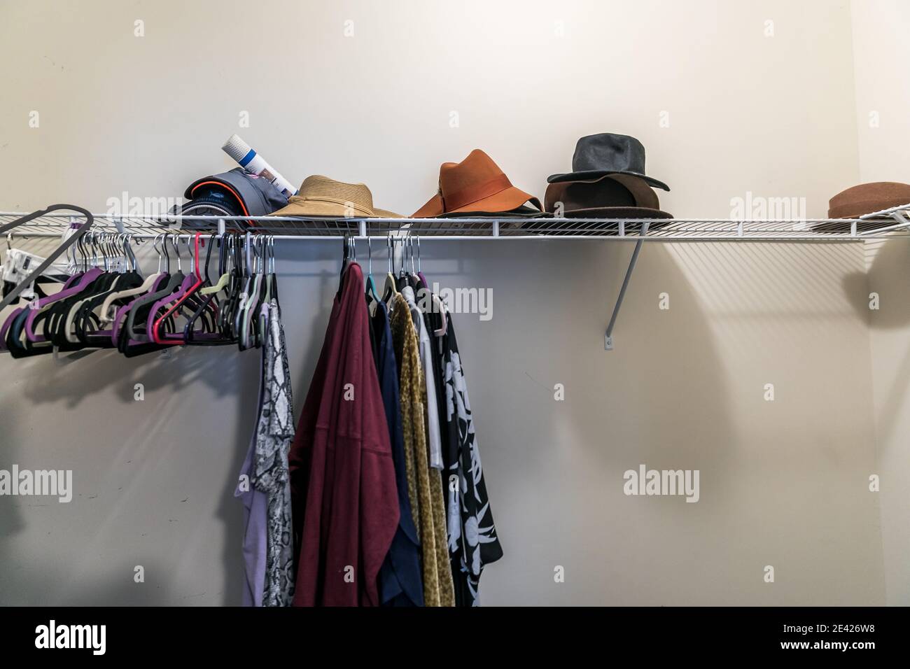 Una passeggiata per lo più vuota in un armadio disordinato con qualche appeso vestiti e cappelli Foto Stock