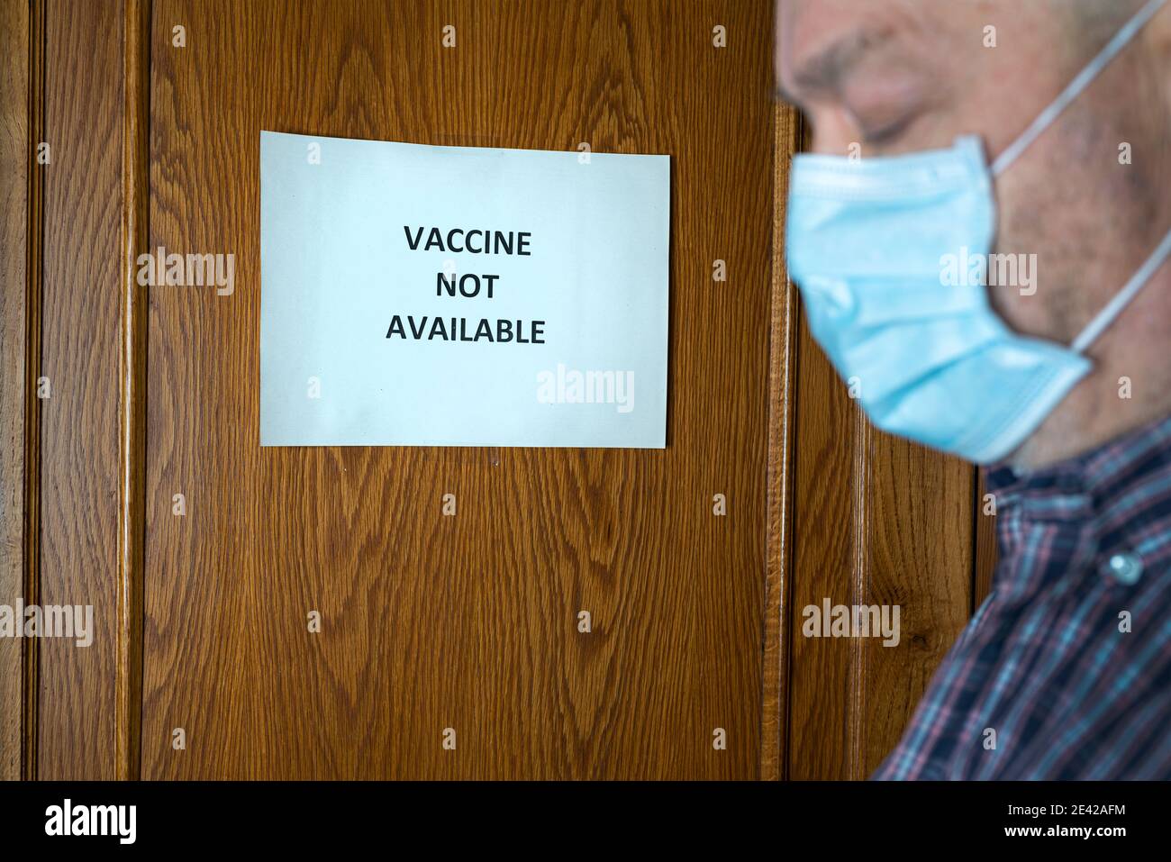 Un uomo davanti ad una porta chiusa con un Segno che recita chiuso perché il vaccino non è disponibile Foto Stock