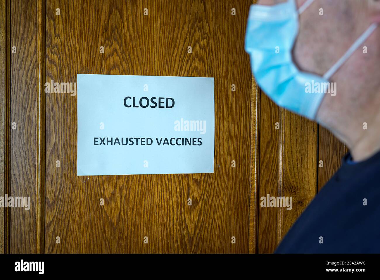 Un uomo davanti ad una porta chiusa con un Segno che legge chiuso perché il vaccino è fuori scorte Foto Stock