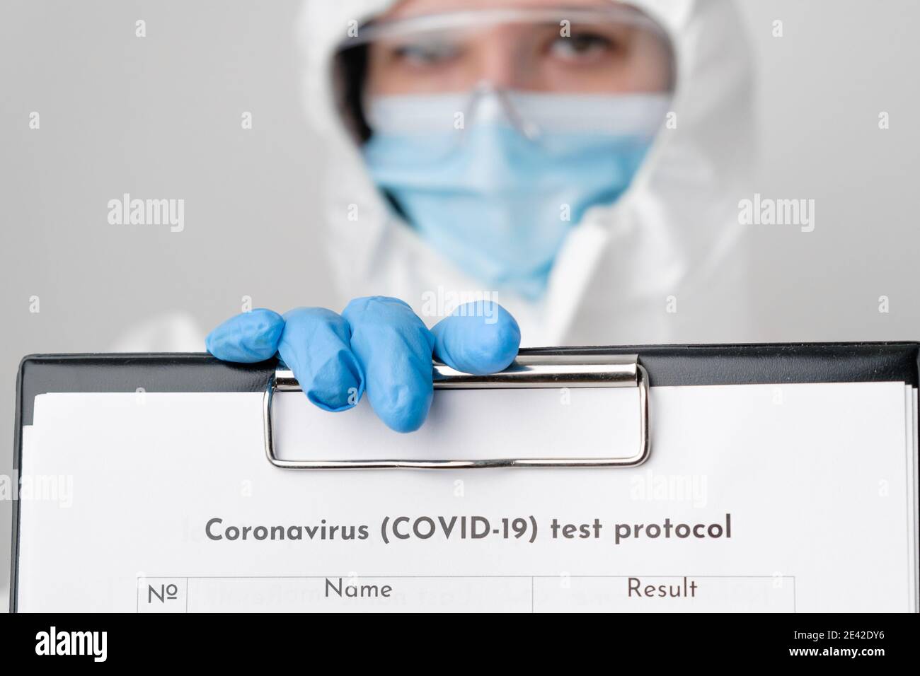 Medico o infermiere in tuta protettiva DPI e guanti di gomma che tengono il protocollo di test medico del coronavirus. Foto Stock