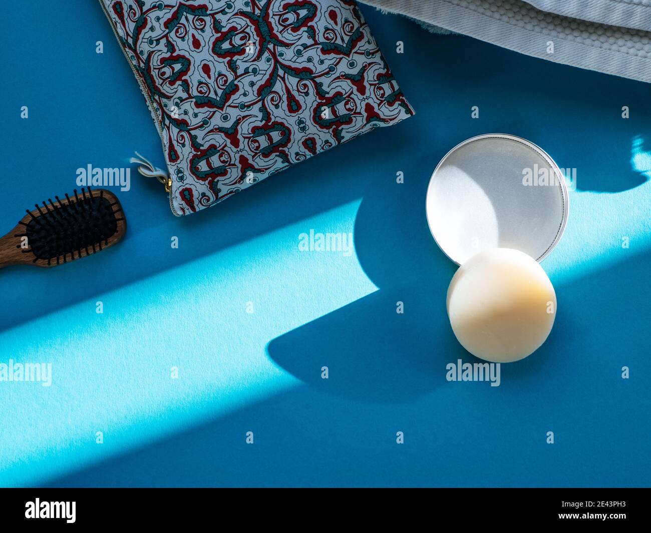 Cura dei capelli ecocompatibile: Shampoo Bar solido e un pennello isolato su sfondo blu Foto Stock
