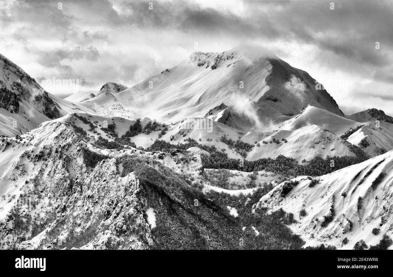 Bianco e nero spettacolare paesaggio di catena montuosa coperto di neve in inverno freddo Foto Stock