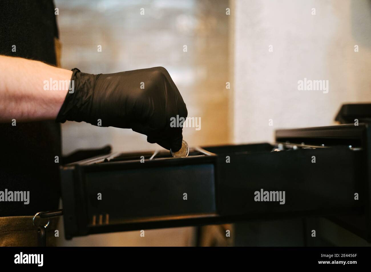 Primo piano di una mano che mette denaro in un registratore di cassa Foto Stock