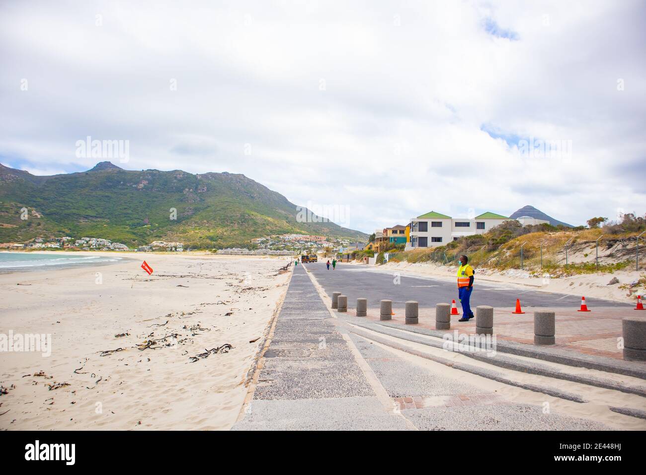 Hout Bay- Città del Capo, Sud Africa - 19-01-2021 lungo parcheggio in cemento chiuso a causa della chiusura. Guardia di sicurezza che indossa la maschera in primo piano. Foto Stock