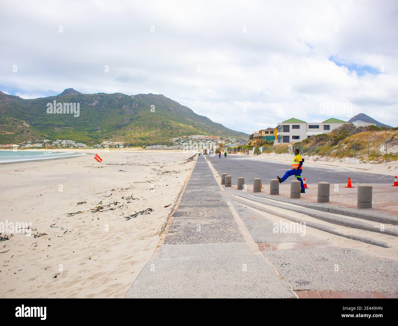 Hout Bay- Città del Capo, Sud Africa - 19-01-2021 lungo parcheggio in cemento chiuso a causa della chiusura. Guardia di sicurezza che indossa la maschera in primo piano. Foto Stock