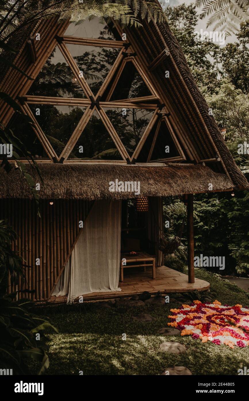 Esterno di una casa di bambù eco in stile tradizionale situata nel mezzo Piante tropicali verdi a Bali in Indonesia Foto Stock